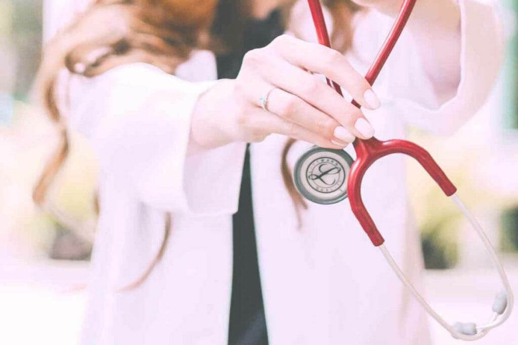 Woman in a white lab coat holding a stethoscope.