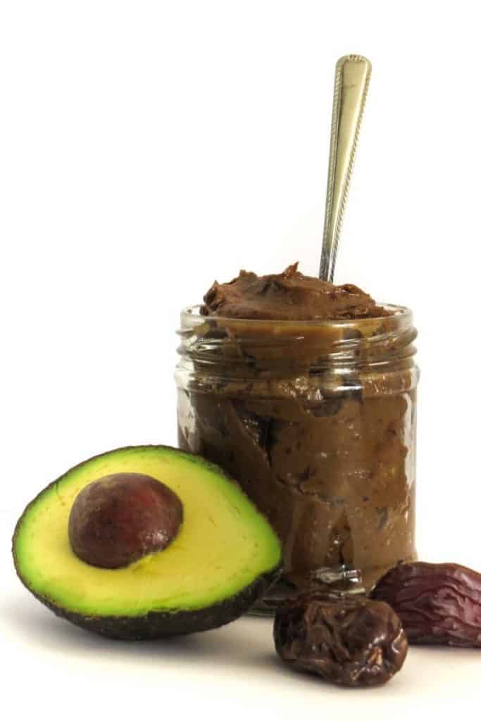 jar of chocolate avocado mousse with half an avocado and two dates side view