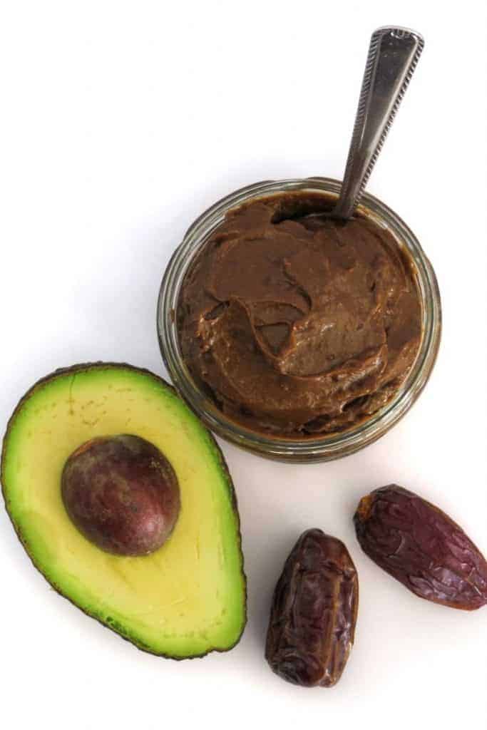 jar of chocolate avocado mousse with half an avocado and two dates overhead view