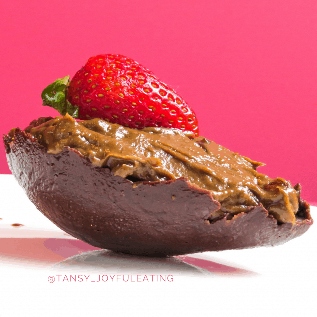half a chocolate avocado egg filled with chocolate avocado mousse and topped with a strawberry