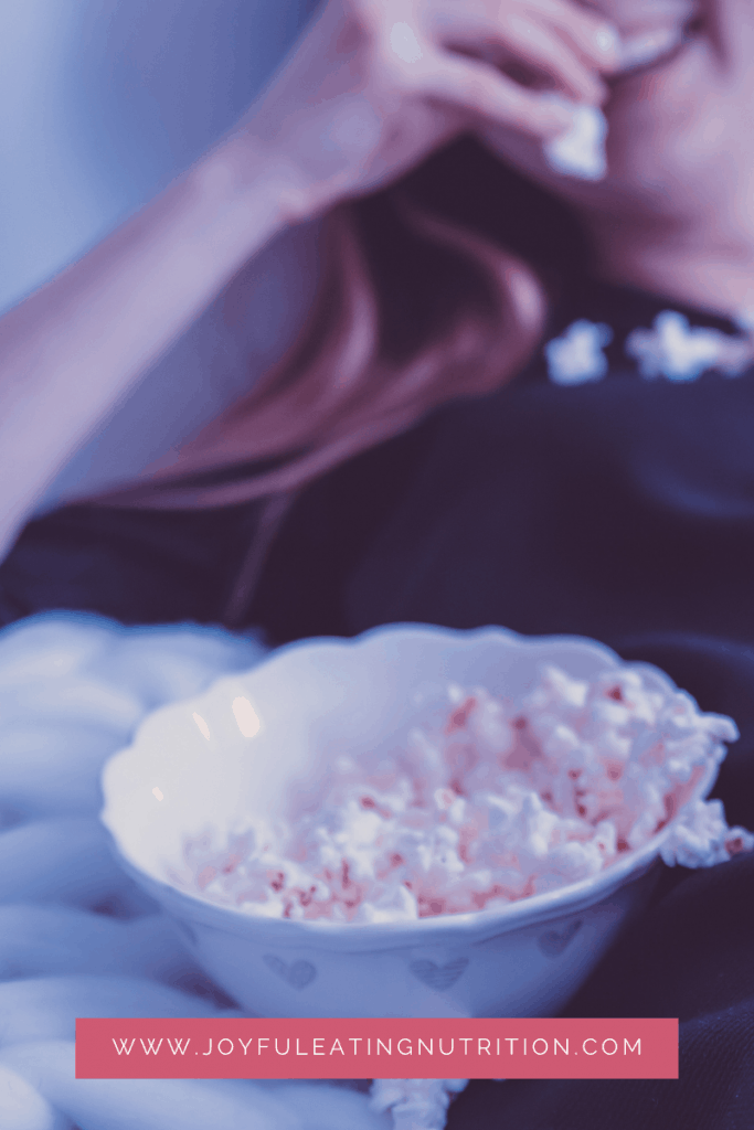 woman lying back on couch eating popcorn