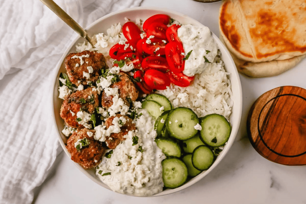 Grain bowl with rice, chicken (or turkey) meatballs served with tzatziki sauce, fresh cucumbers and tomatoes.
