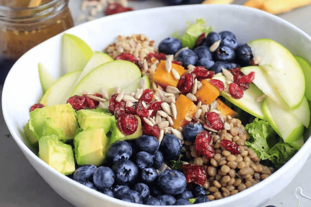 Lentil and rice grain bowl with apple, blueberries, pumpkin, avocado, dried cranberries and sunflower seeds