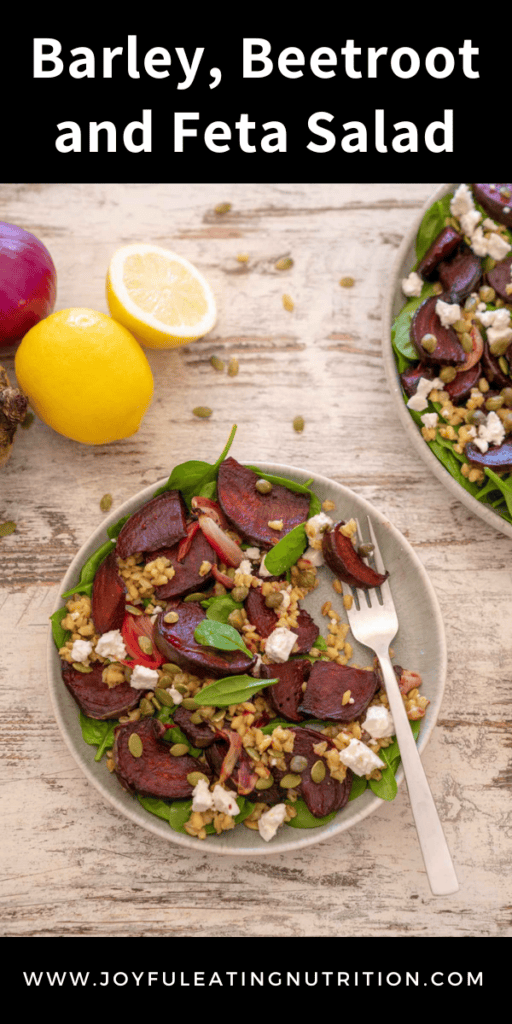 Overhead photo of barley, beetroot and feta salad on wooden surface, with lemon, red onion and fresh beetroot with recipe title.