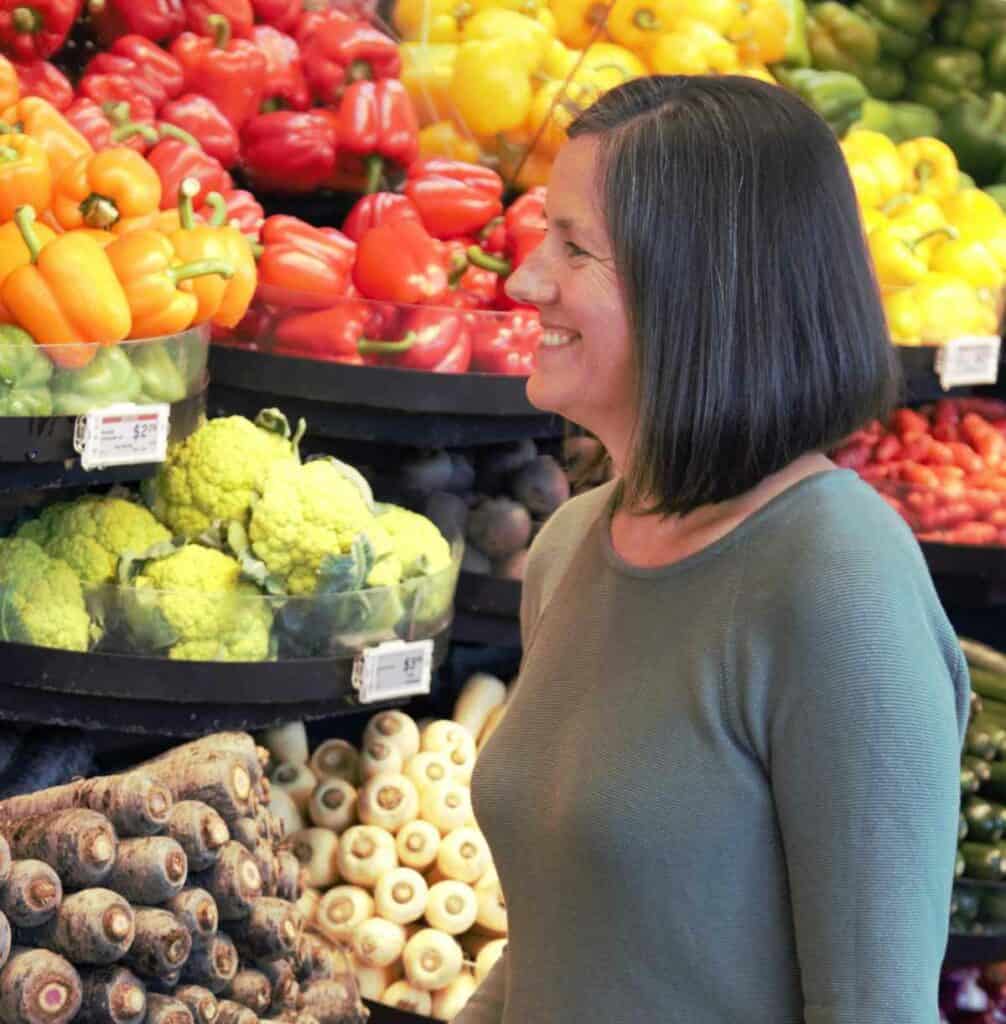 Nutritionist, Tansy Boggon standing in front of produce in the supermarket.